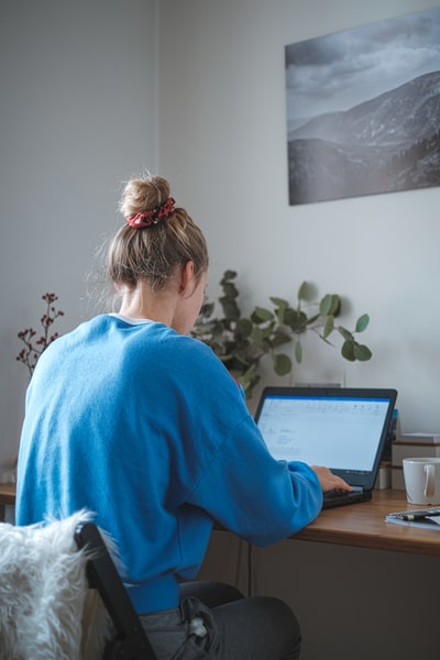 穿着蓝色毛衣的女人坐在笔记本电脑前
